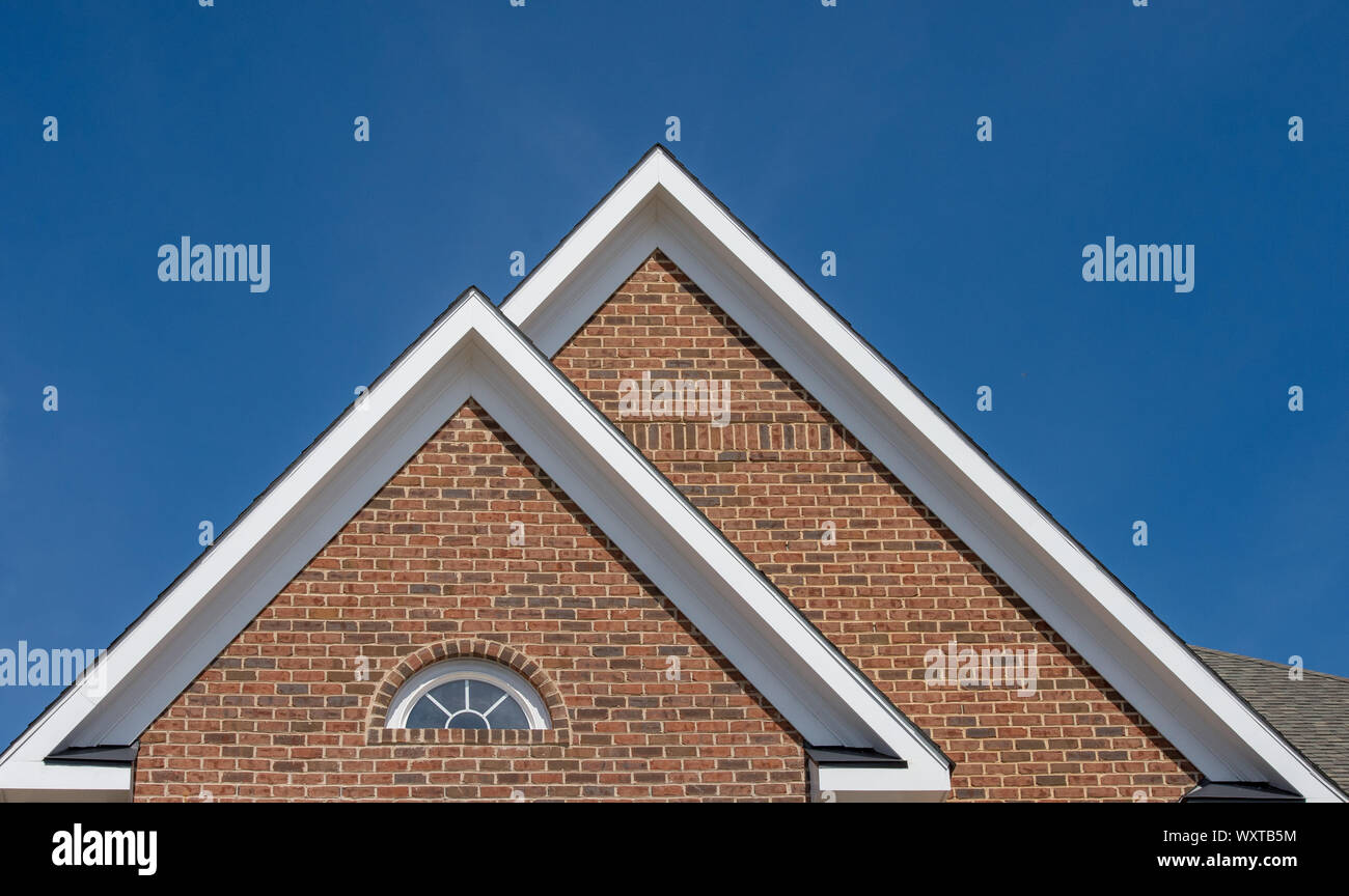 Di plastica o di legno tetto bianco decorazione gable, corbel, feritoia su una nuova costruzione di lusso singolo americano casa di famiglia nella costa orientale USA con blue s Foto Stock