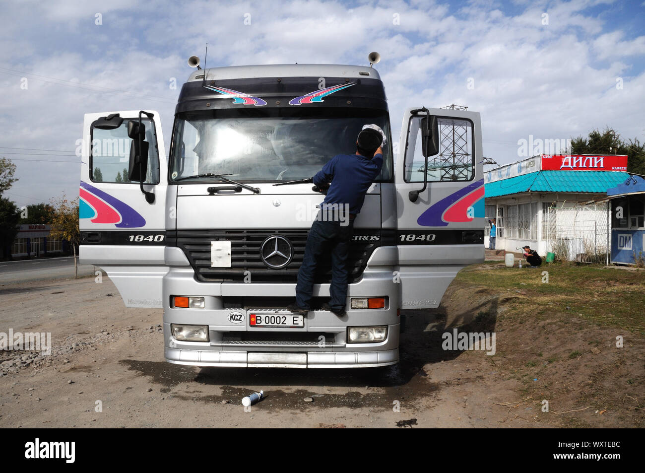 Un driver del Kirghizistan lava i parabrezza della sua Mercedes Actros carrello lungo la strada del Pamir in Kirghizistan Foto Stock