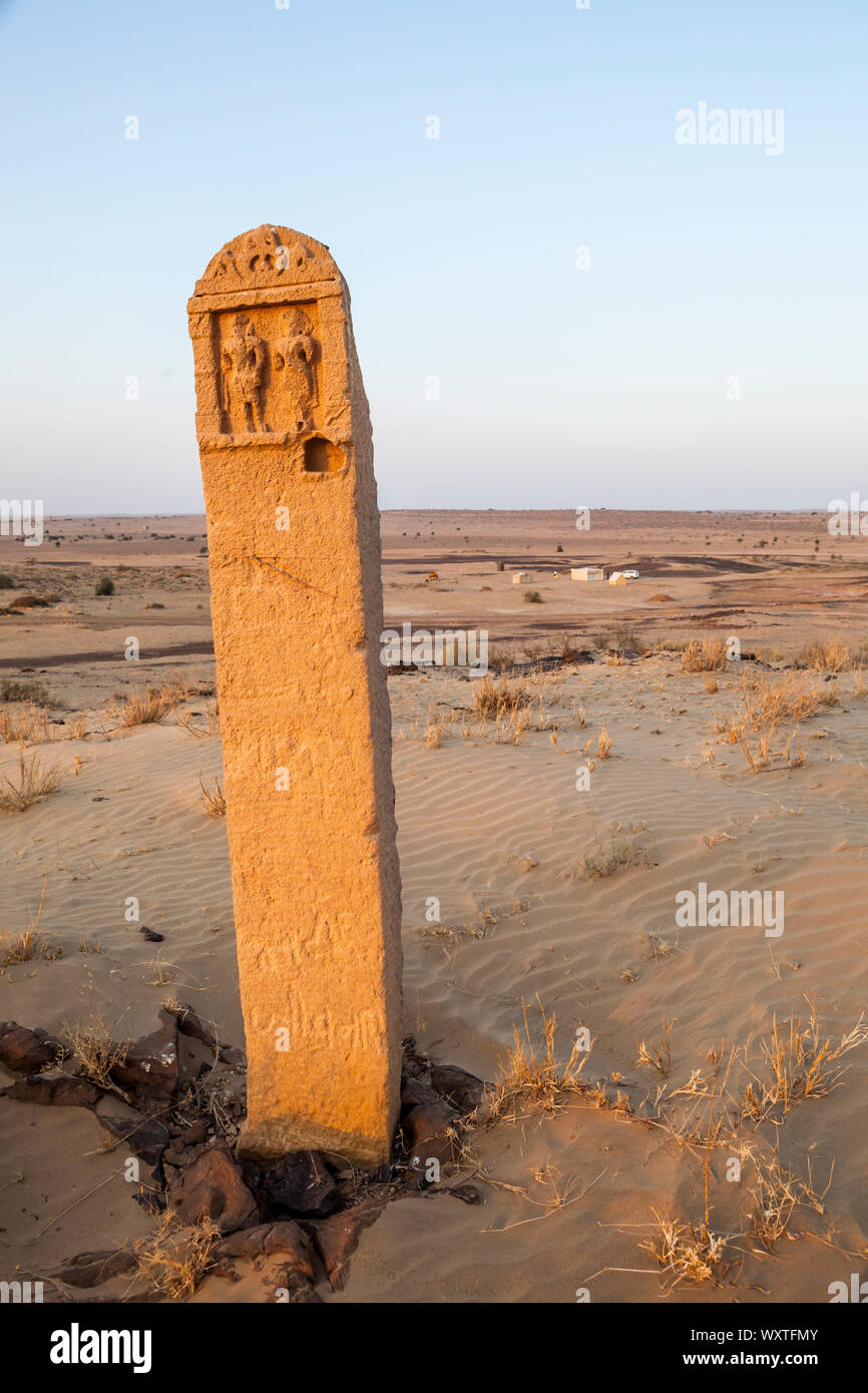 Un marcatore di pietra su una collina di sabbia al di sopra di un campo che è parte di un turista trekking cammello nel deserto del Thar del Rajasthan, India. Foto Stock