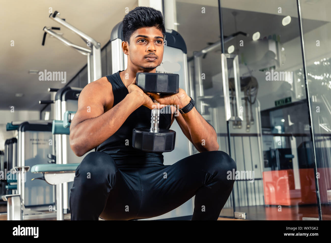 Giovane uomo squat con manubri in palestra Foto Stock