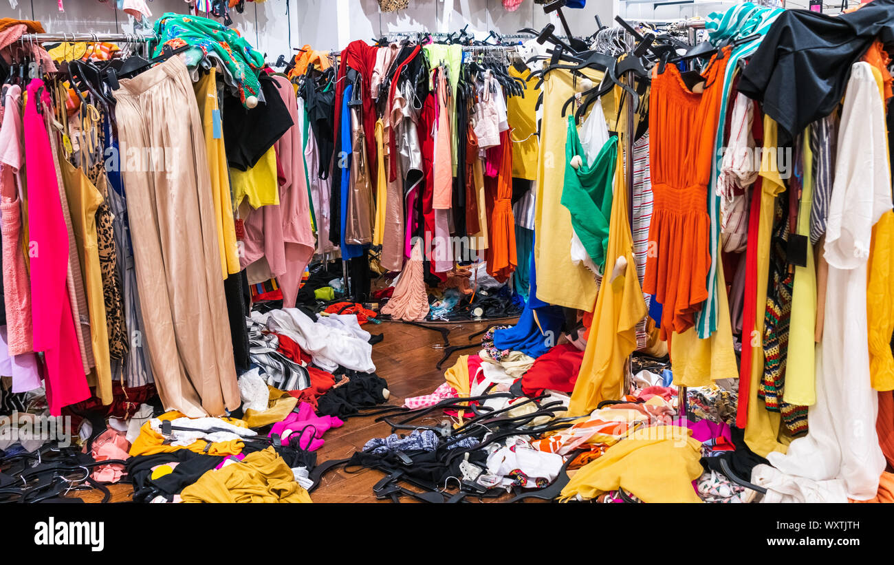 Gioco disordinato sezione in un negozio di abbigliamento, con indumenti  colorati su rack e sul pavimento Foto stock - Alamy