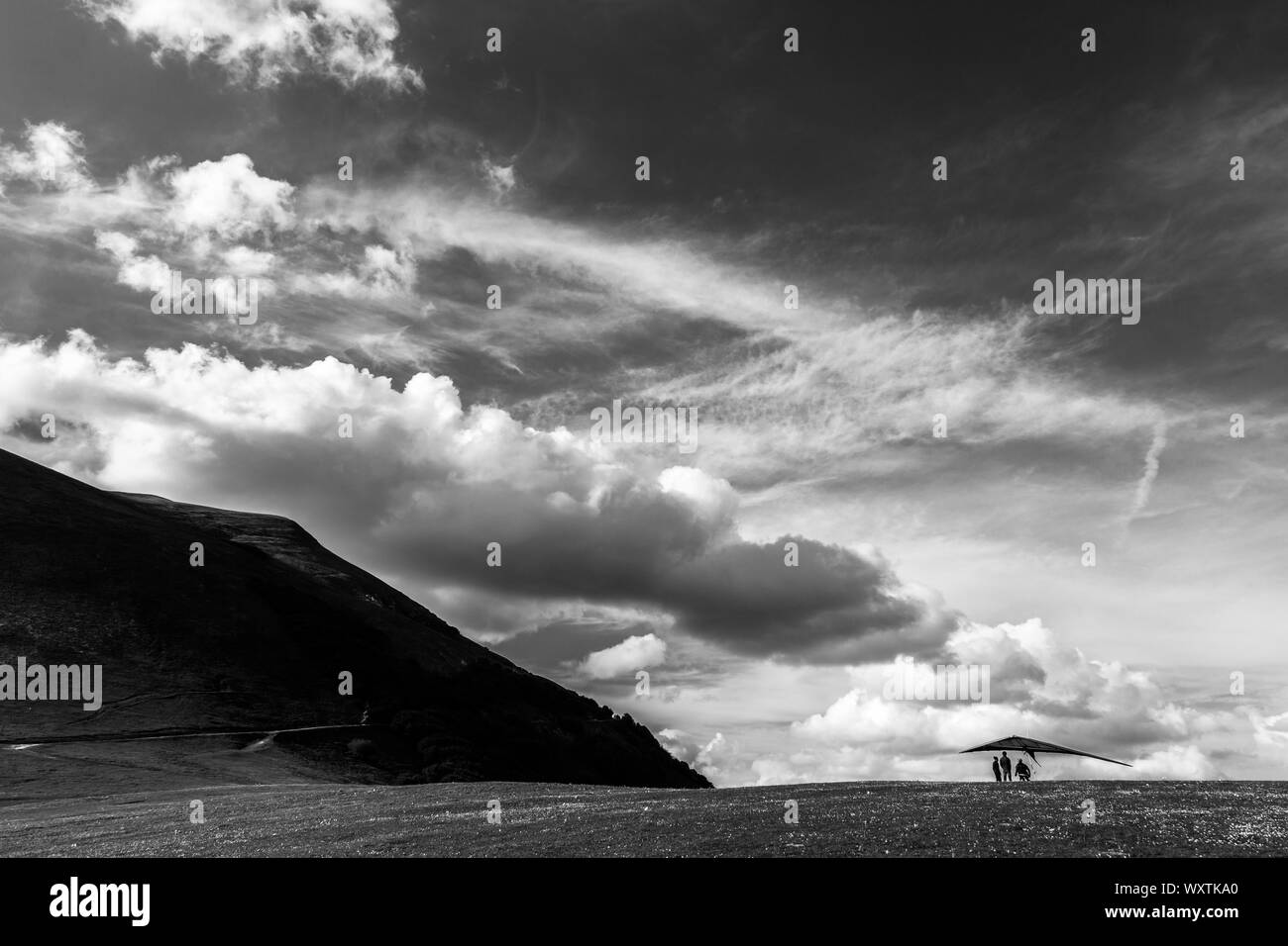 Un parapendio sul terreno su Mt. Cucco (Umbria, Italia) sotto un cielo profondo con grandi nuvole bianche Foto Stock