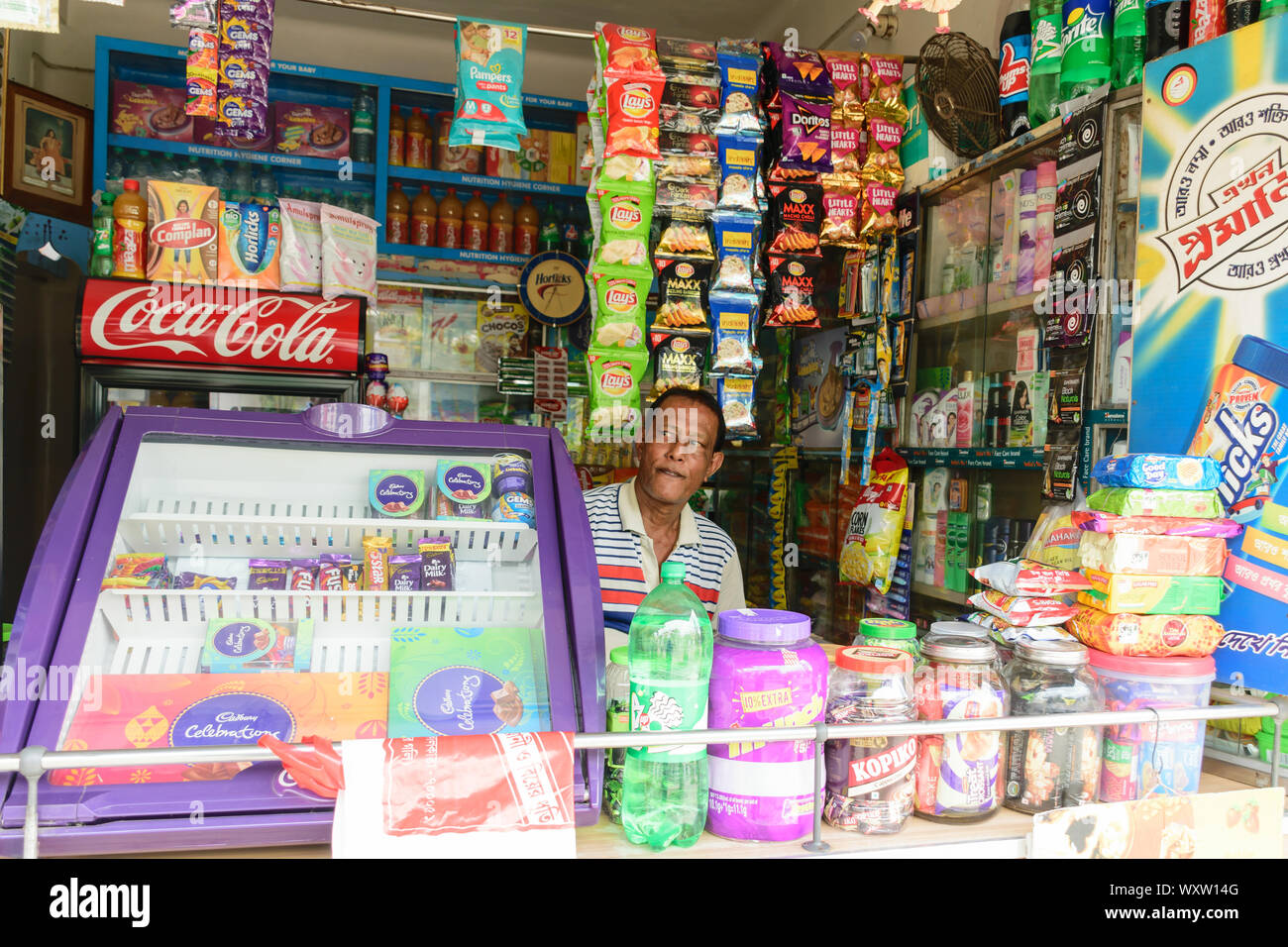 Kolkata, West Bengal, India 1 gennaio 2019 - Un negozio di generi alimentari al dettaglio proprietario del negozio in cerca di clienti da dentro il suo store. Foto Stock