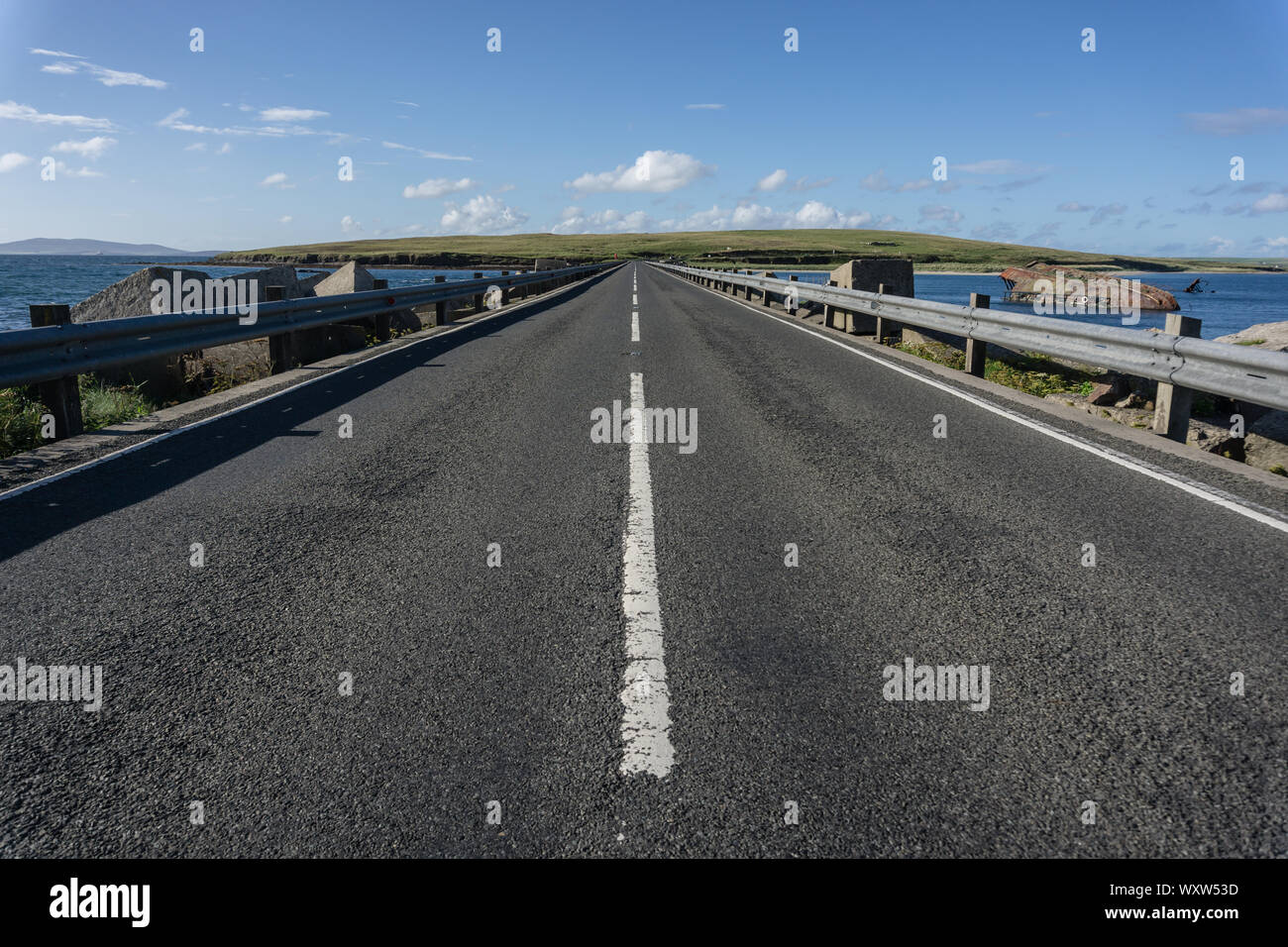 Vista della strada che attraversa la barriera di Churchill 3, Scapa Flow, Orkney, Scozia Foto Stock