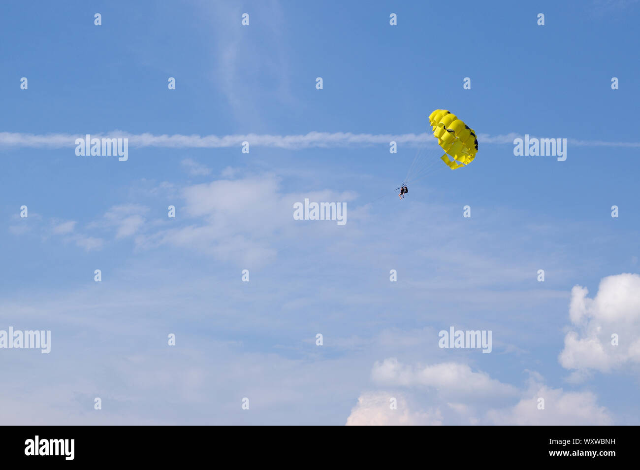 Due persone sono a volare su un giallo paracadute trainato da la fune contro il cielo blu. Vacanze attività sportive. Foto Stock