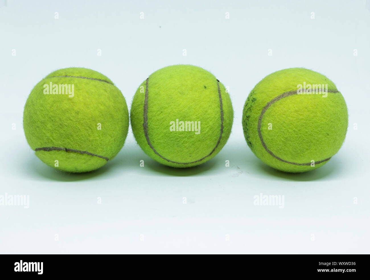 Tre usato, neon verde le palline da tennis sono allineate in una fila  isolata con uno sfondo bianco Foto stock - Alamy