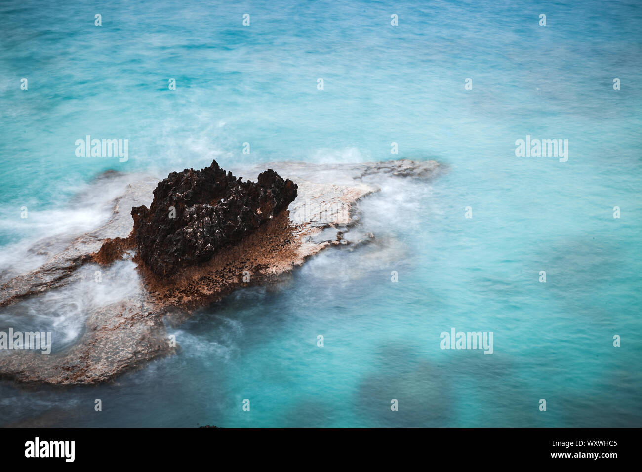 Mare Mediterraneo. Il paesaggio costiero con roccia scura in blu luminoso l'acqua. Una lunga esposizione foto sfocate con effetto dell'acqua. Ayia Napa, isola di Cipro Foto Stock