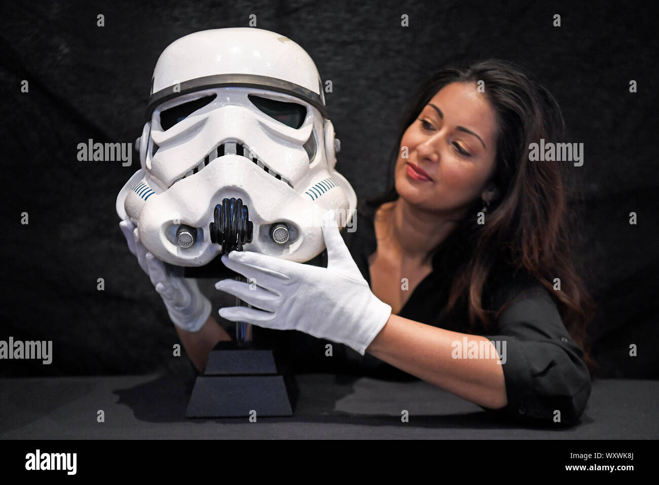Un puntello dipendente del negozio trattiene una schermata-abbinato Tantive IV Stormtrooper casco da Star Wars: Una nuova speranza, in un'asta anteprima, davanti a loro la vendita di memorabilia di intrattenimento al BFI IMAX a Waterloo, Londra. Foto Stock