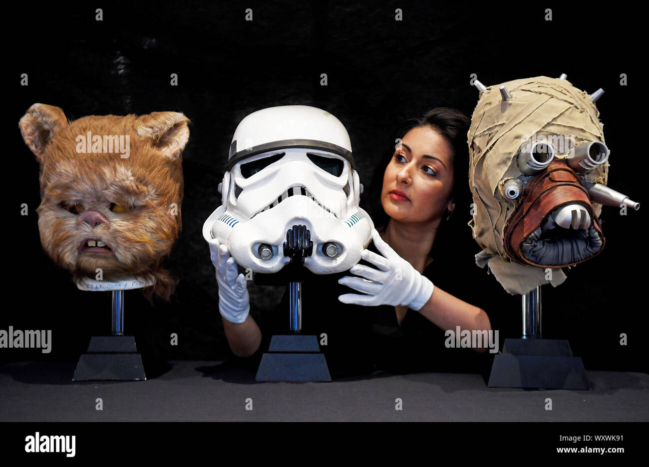 Una schermata-abbinato Tantive IV Stormtrooper casco (centro) da Star Wars: Una nuova speranza, che è stimato da vendere per tra ??120.000 - ??180.000, a fianco di un prototipo Tusken Raider maschera (a destra) e una maschera di Ewok (sinistra) sul display al Prop Store anteprima di d'Aste, davanti a loro la vendita di memorabilia di intrattenimento al BFI IMAX a Waterloo, Londra. Foto Stock