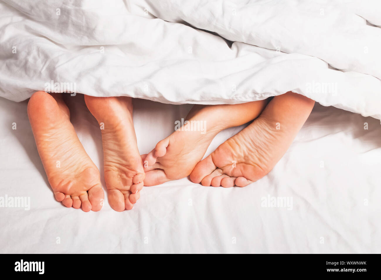 Morchie di un uomo e di una donna che dorme nel letto con lenzuola bianche di close-up Foto Stock