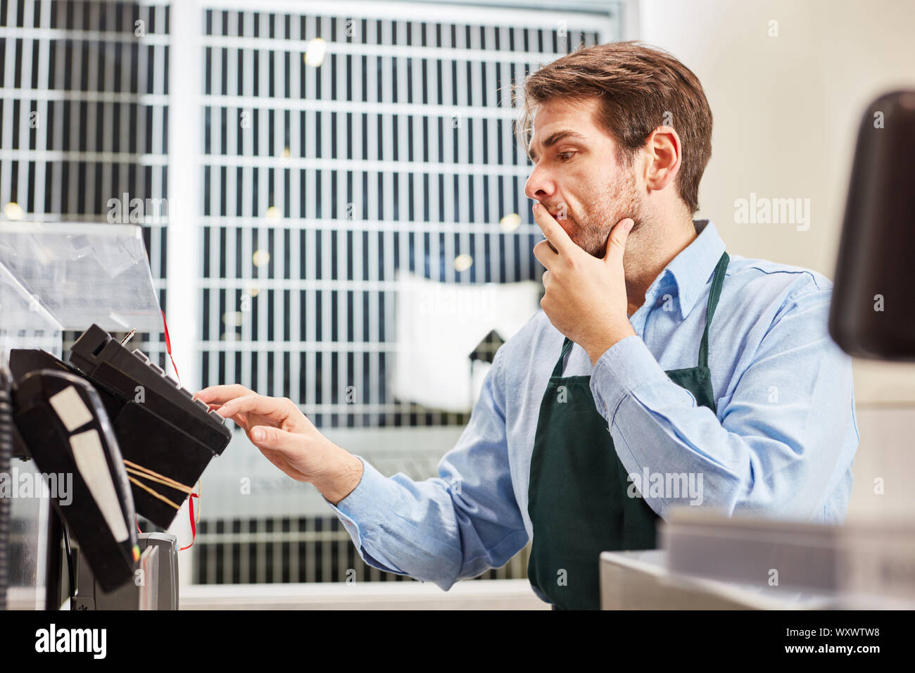 Giovane uomo come un cassiere ha un problema di gestione della cassa nel supermercato Foto Stock