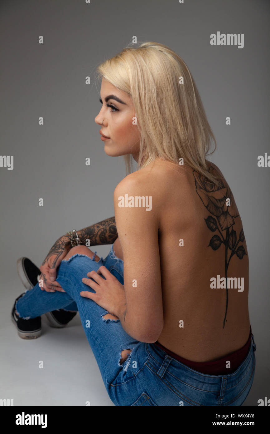 Una giovane e bella donna con tatuaggi seduti con la schiena verso la telecamera. Foto Stock