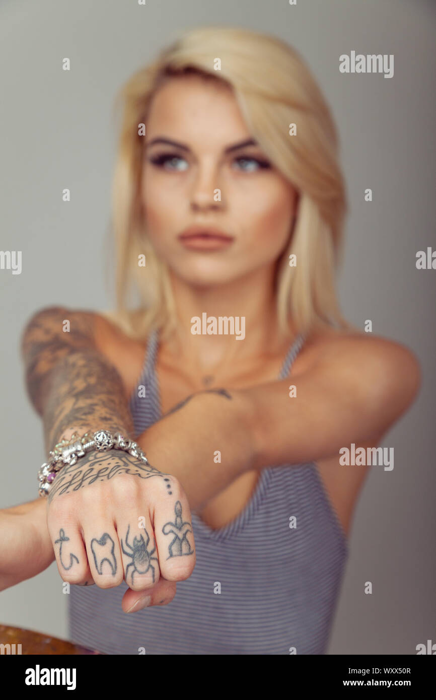 Donna con tatuaggi sulle sue dita tenendo la mano verso la telecamera. Foto Stock