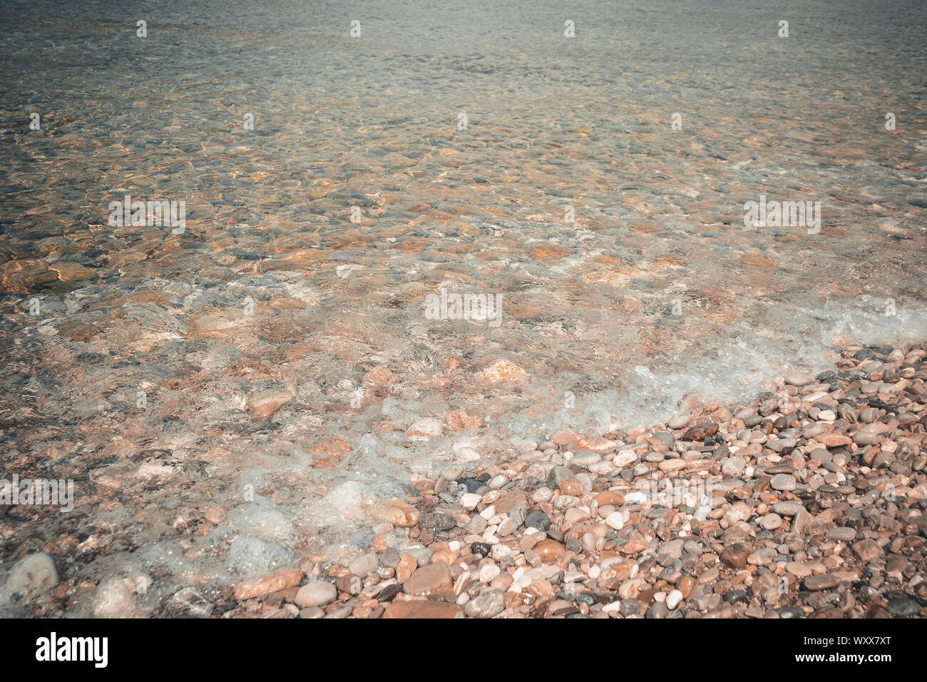 Mare ciottoli e pietre sott'acqua. Tessiturali fondale attraverso chiare e trasparenti acque blu. Sfondo naturale. Foto Stock