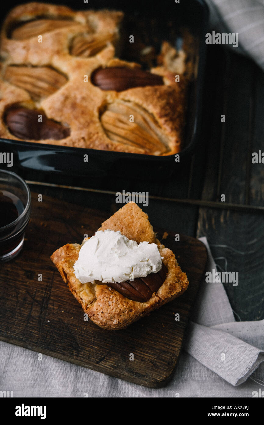 Caduta francese torta di pere in un quadrato nero ceramica stoviglia con il grigio igienico. Fotografia di alimentare il concetto di styling. Overhead, flatlay Foto Stock