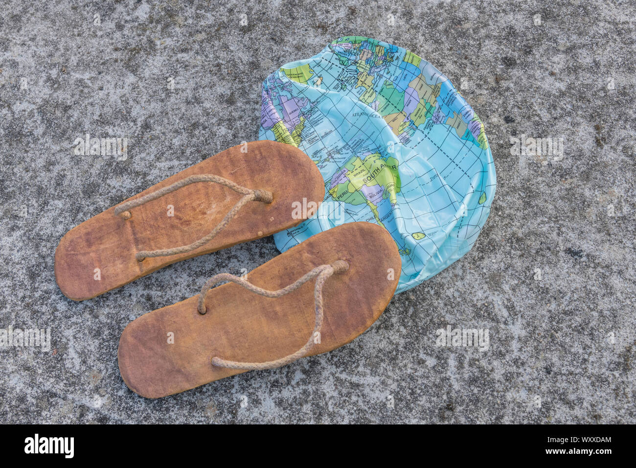 Indossato hippy flipflops & globo sgonfiato sulla superficie di calcestruzzo. Metafora terra piatta, flat earthers, teorie cospirative, piano terra prove, pseudoscience Foto Stock