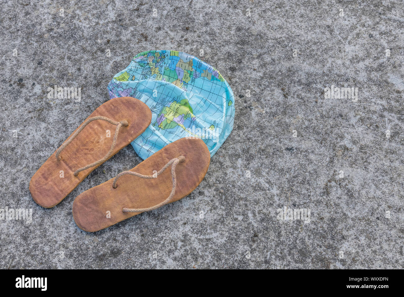 Indossato hippy flipflops & globo sgonfiato sulla superficie di calcestruzzo. Metafora terra piatta, flat earthers, teorie cospirative, piano terra prove, pseudoscience Foto Stock