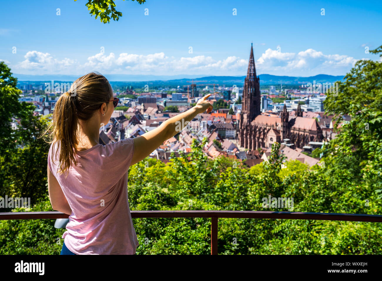 Germania, giovane bionda bellezza ragazza in piedi sopra i tetti della città di Freiburg im Breisgau quartiere storico e popolare di Muenster cattedrale in estate wit Foto Stock