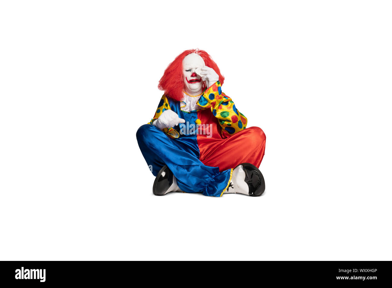 Triste clown seduto sul pavimento e pianto Foto Stock