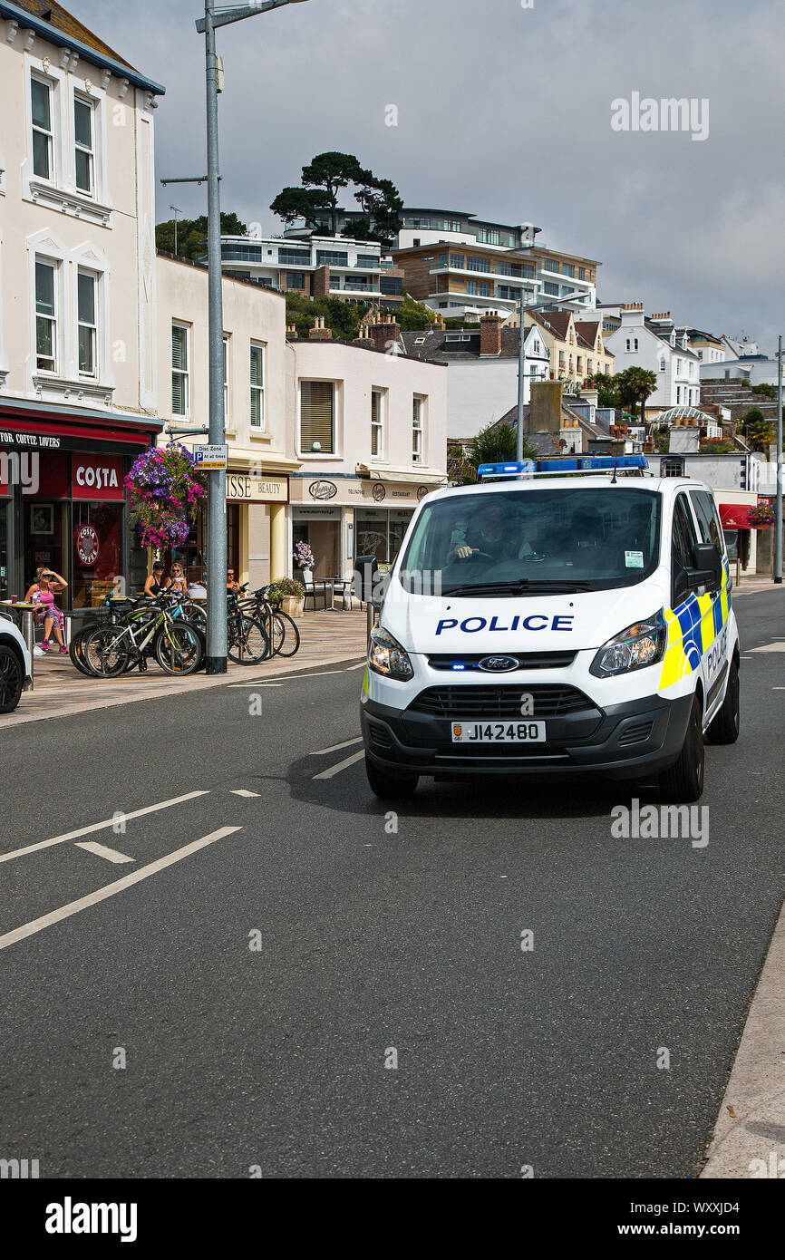 Una polizia van con blues e a due passi operativi attraverso la strada principale a St Aubin, Jersey, Isole del Canale Foto Stock