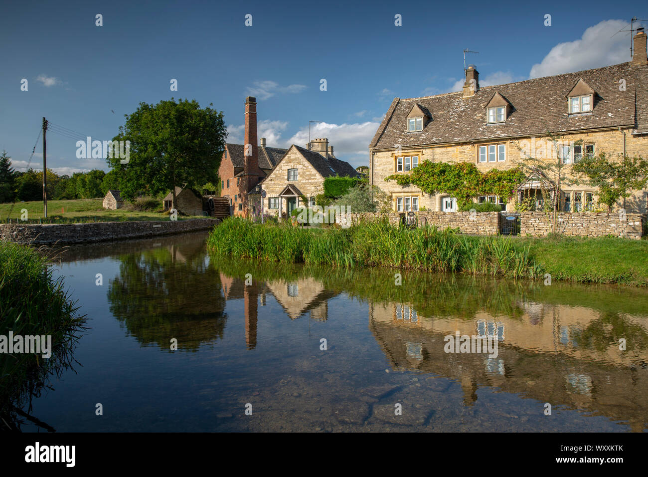 Lower Slaughter, Gloucestershire e il vecchio Mil e il Fiume Windrush mostra le riflessioni. Foto Stock
