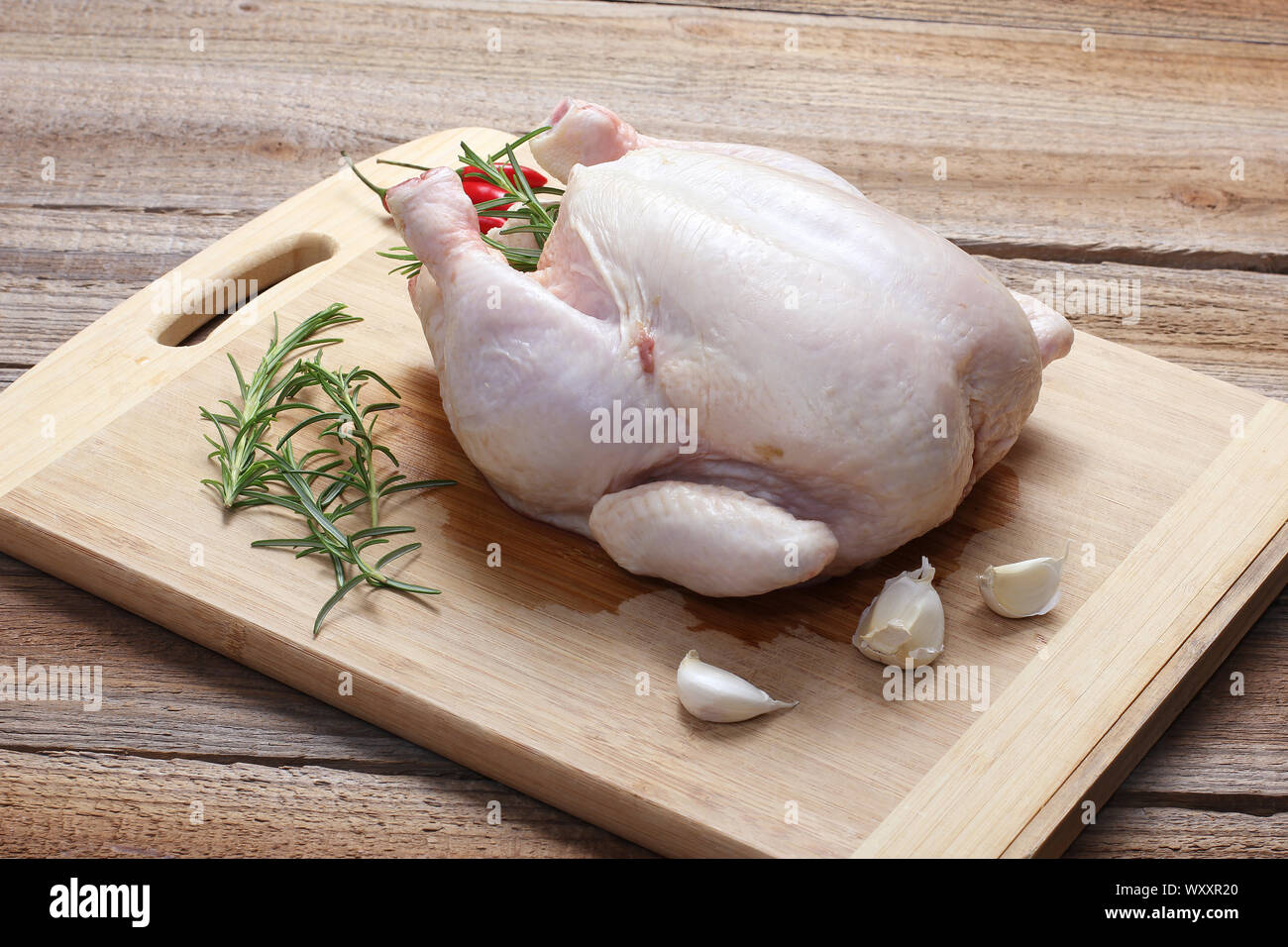 Il pollo intero con la pelle sul tagliere Foto Stock