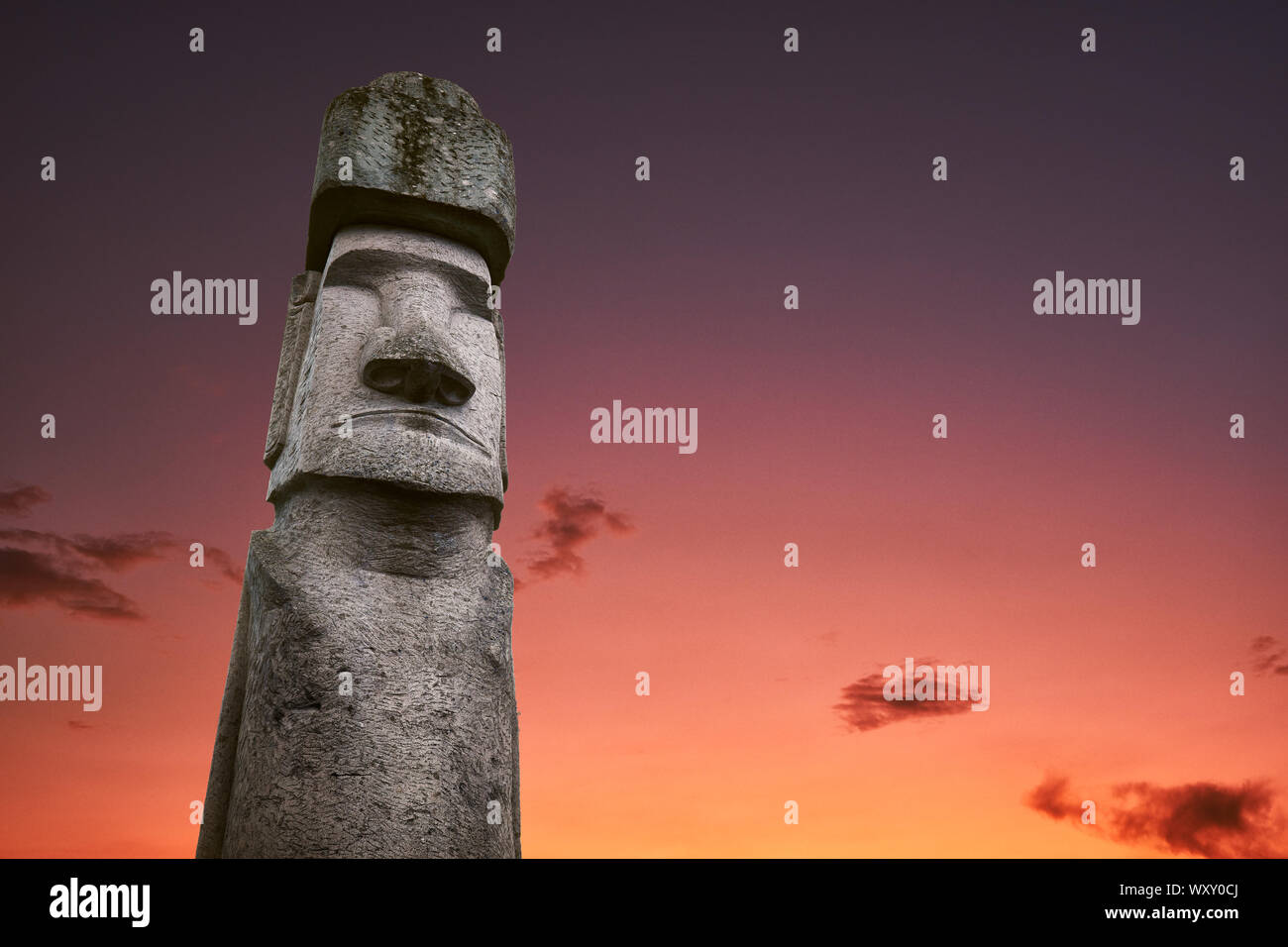 Un antica statua di un Moai da Isola di Pasqua e la civiltà perduta di Rapa Nui, con un romantico e drammatico il cielo al tramonto con le nuvole in backg Foto Stock