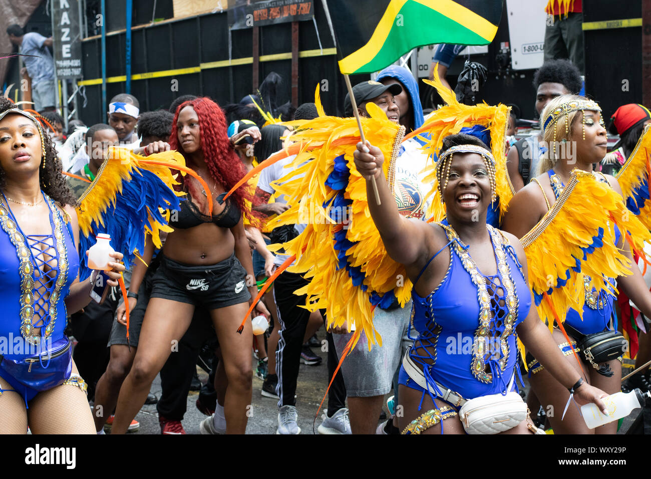 Tanzend zu lauter Musik laufen Teilnehmer der West Indian Day Parade di New York City Un den Zuschauern vorbei und animieren diese. Foto Stock