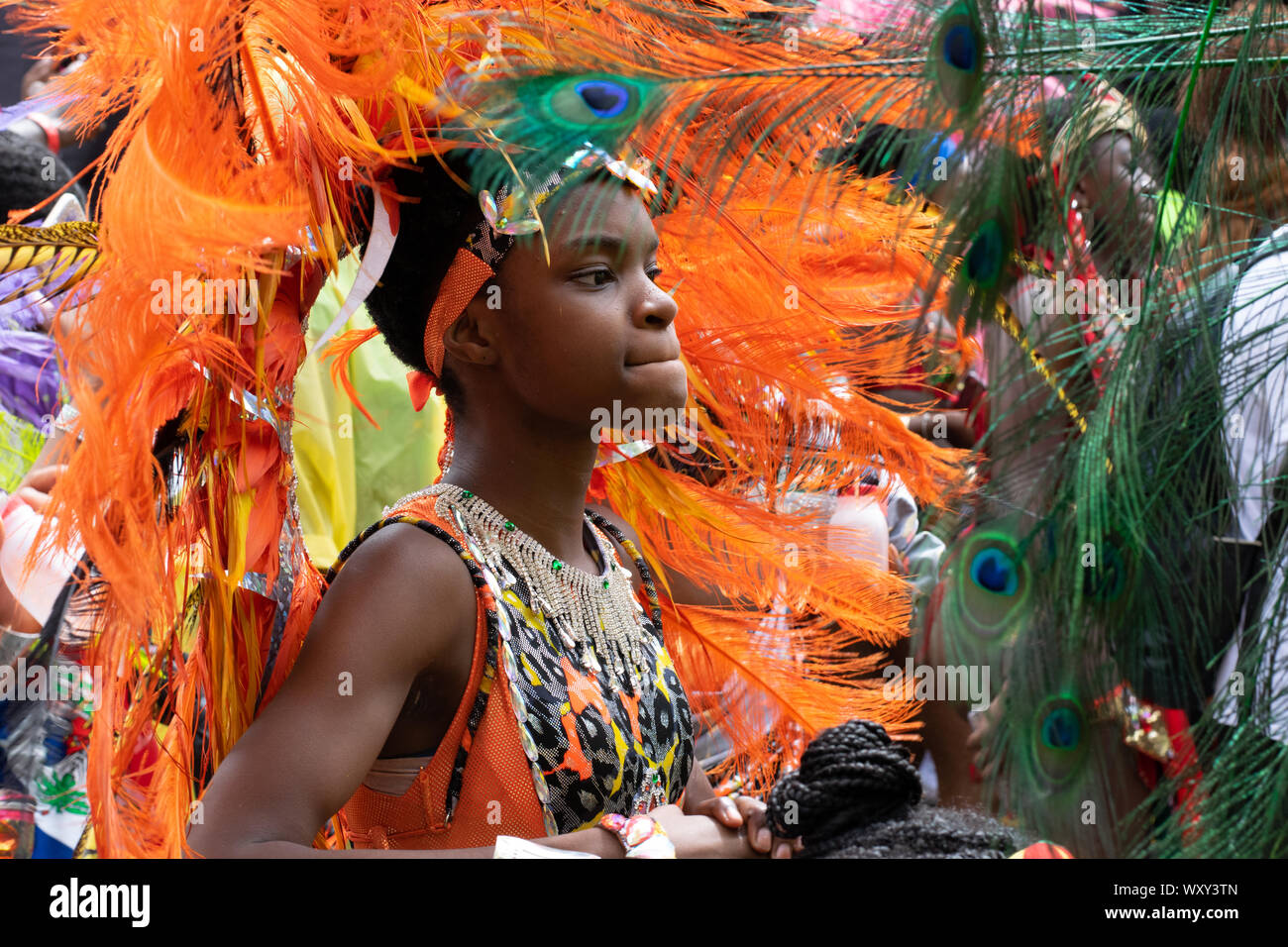 Junger Mann oder junge Frau im Tanz vertieft, in arancione bekleidet mit schönem Karnevalskostüm mit Schmuck aus Federn. Foto Stock