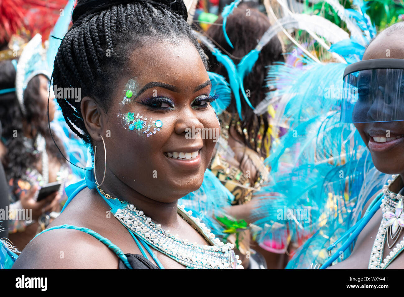 Eine lateinamerikanisch oder afrikanisch aussehende Frau lächelt in die Kamera. Sie nimmt Teil an der West Indian Day Parade di New York City Foto Stock