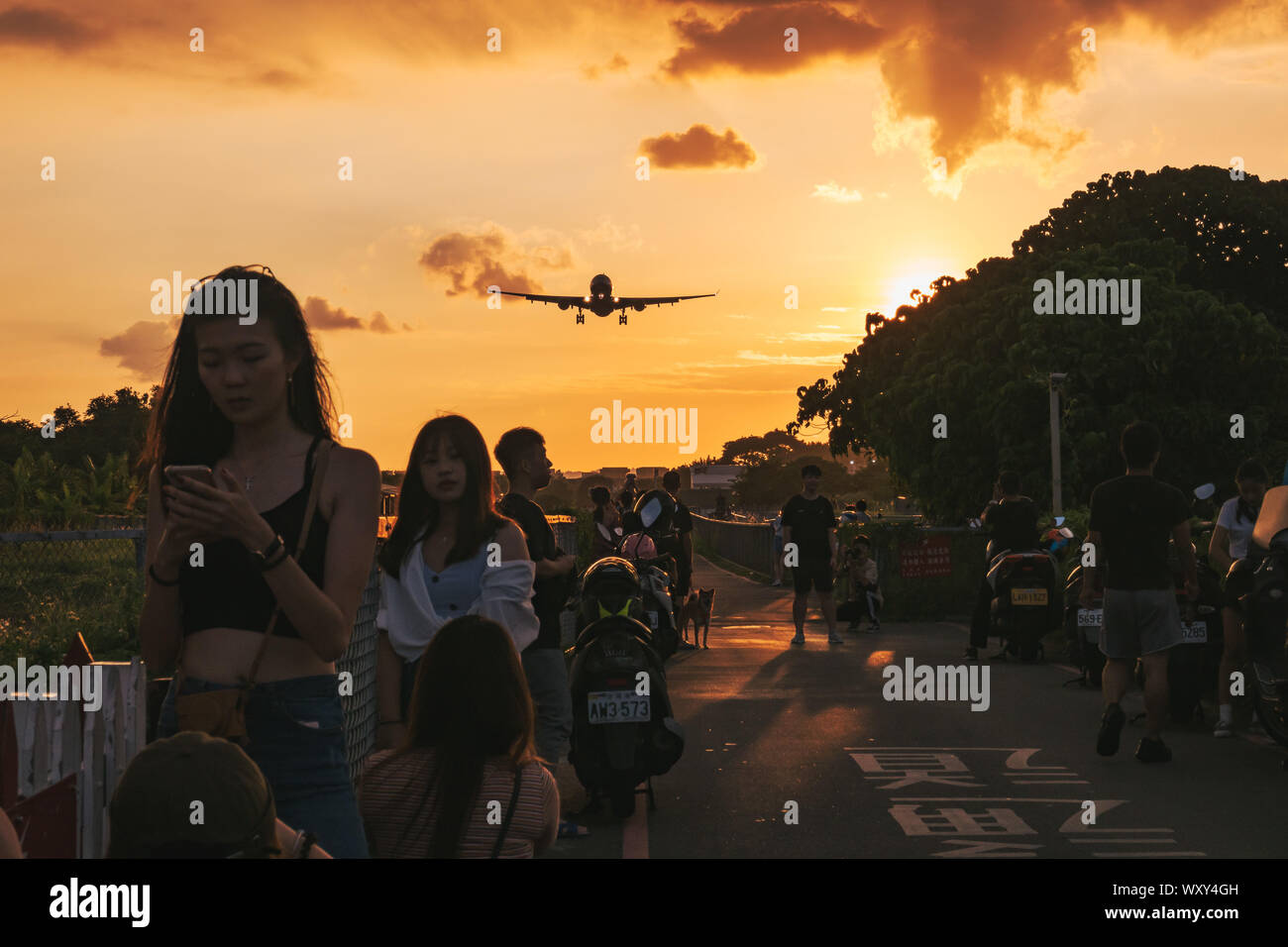 Gli spettatori si preparano per una foto come un Airbus A330 si avvicina al tramonto a terra a Taipei Aeroporto Songshan, Taiwan Foto Stock