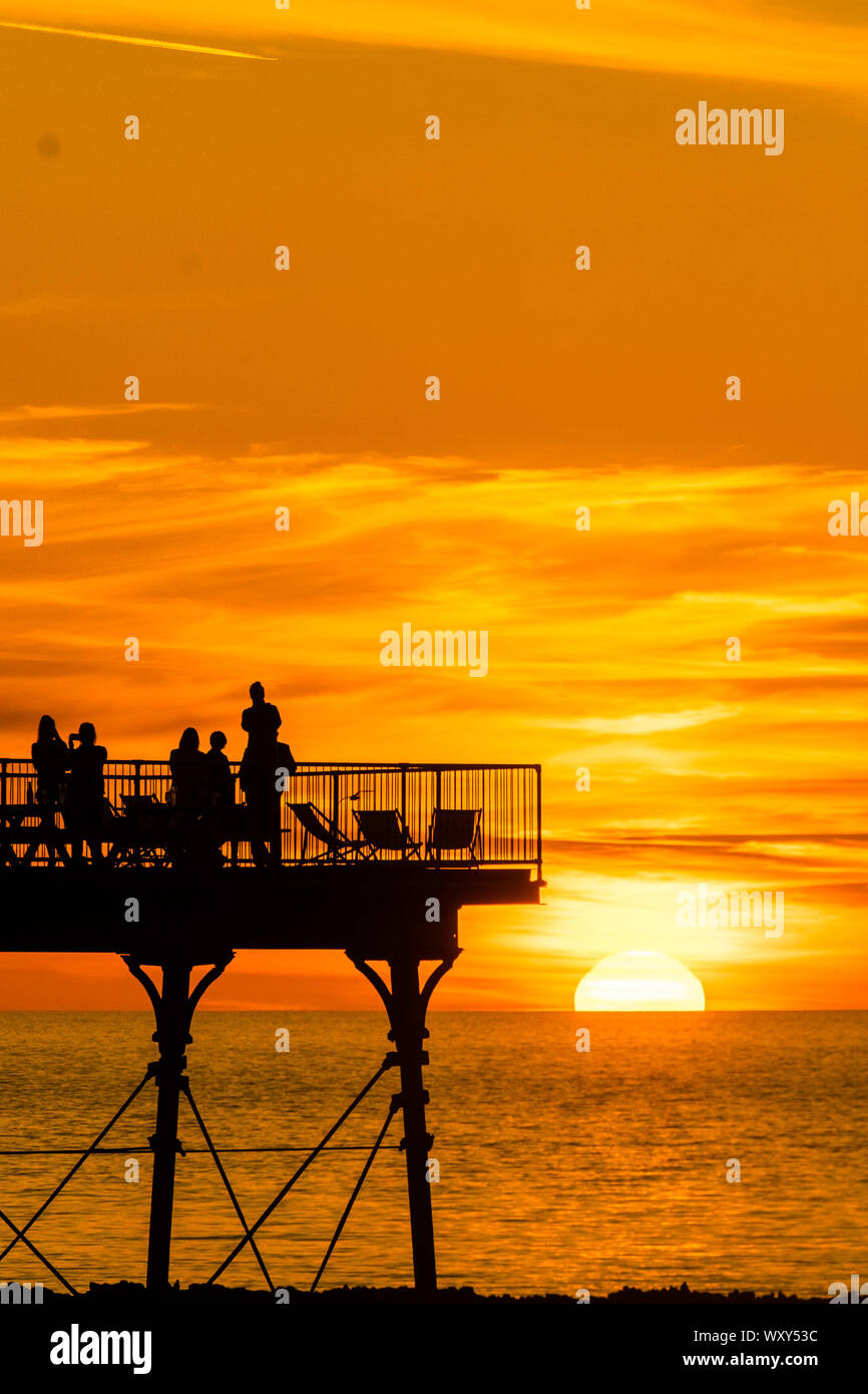 Aberystwyth, UK. Xviii Sep, 2019. Aberystwyth Wales UK, mercoledì 18 settembre 2019 il sole che tramonta gloriosamente su Cardigan Bay sagome di persone sul molo sul mare alla fine di una giornata di inviolata il cielo limpido e il caldo sole di settembre in Aberystwyth , come il 'estate indiana' calore mini-onda continua nel corso di molte delle parti di souther della UK Credit: keith morris/Alamy Live News Foto Stock