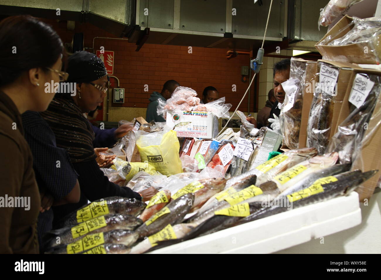 Gli operatori di mercato in un mercato del pesce in tutto il mondo occidentale. Moderno la mattina presto gli operatori nel mercato del Pesce di Billingsgate a Londra, Inghilterra, Regno Unito. Produrre frutti di mare dalla Scozia, Galles, Irlanda, Inghilterra, UNIONE EUROPEA E RESTO DEL MONDO. Il commercio internazionale. Le piccole imprese. Il baratto. La negoziazione. Arte della trattativa. Nessuna trattativa. Trattativa. Le masse di risorse. Gli stock ittici. Foto Stock