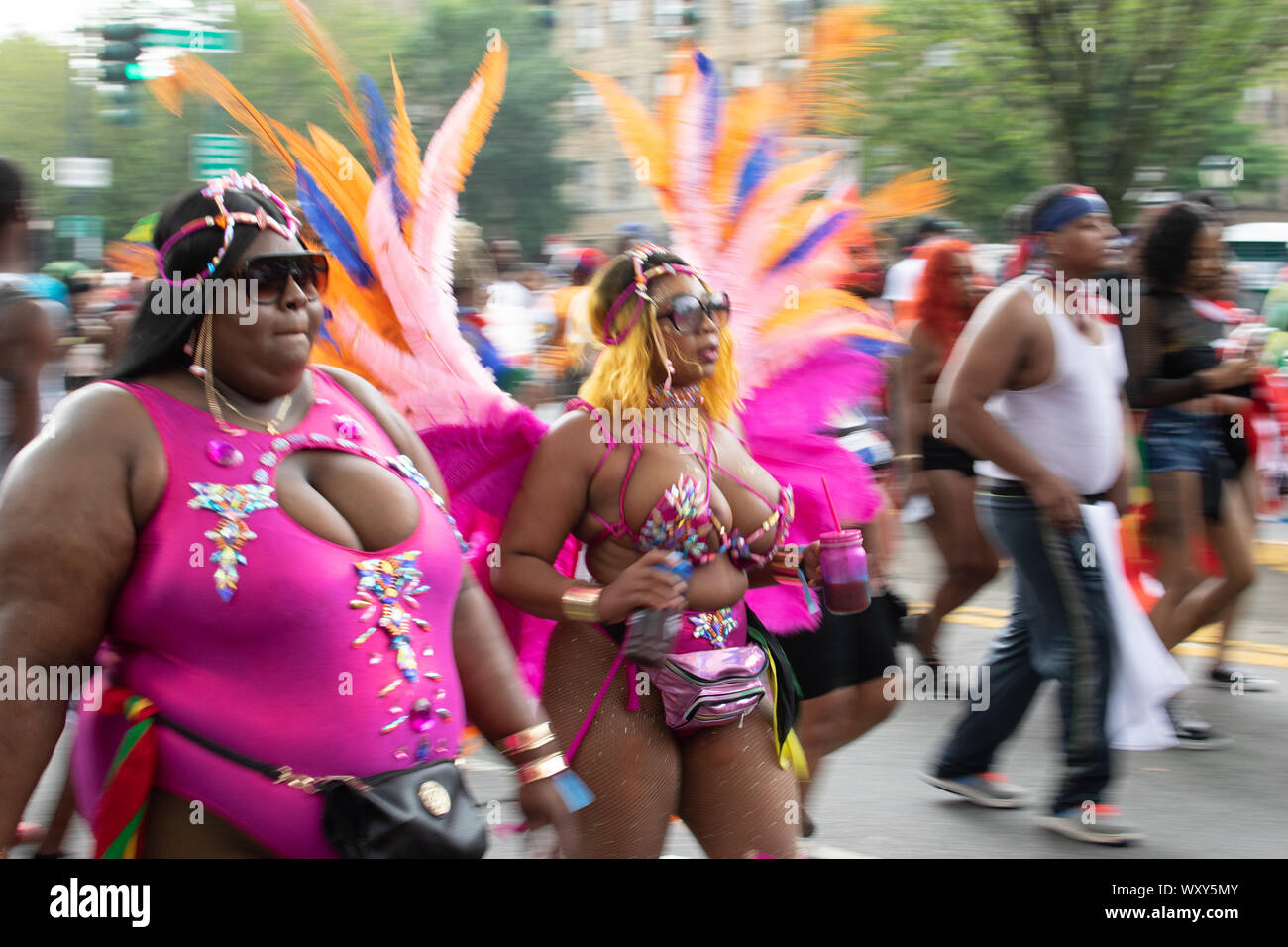 Tanzend zu lauter Musik laufen Teilnehmer der West Indian Day Parade di New York City Un den Zuschauern vorbei und animieren diese. Hier sind zwei ero Foto Stock