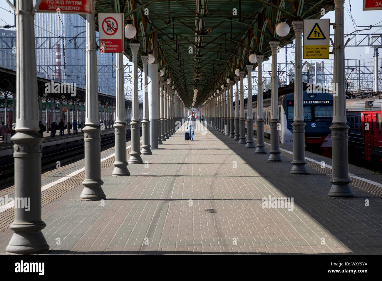 La gente a piedi sulla piattaforma di Mosca Belorussky stazione ferroviaria con treni pendolari e treni a lunga percorrenza a Mosca, Russia Foto Stock