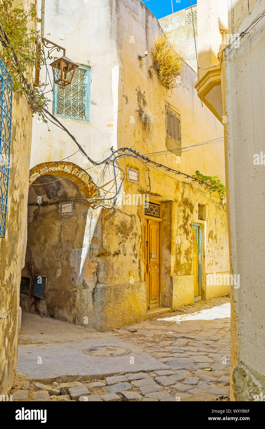 L'ombreggiato backstreet di Bizerte Medina con edifici squallido, passa ad arco, sbriciolare intonaco sulle pareti e lanterne wintage, Tunisia Foto Stock