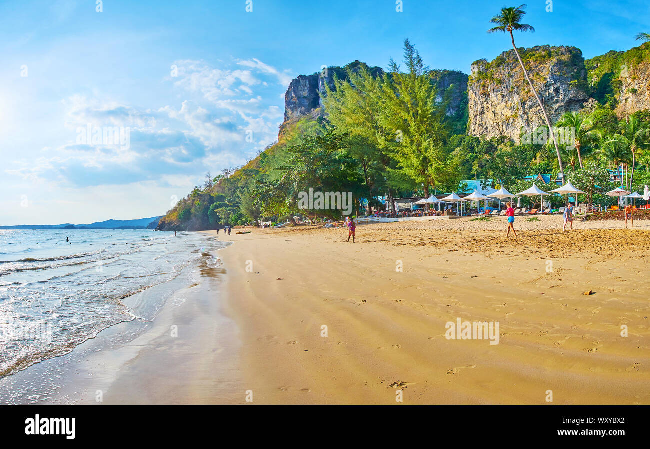 AO NANG, Tailandia - 25 Aprile 2019: La lunga tideline di Centara Grand Beach con la linea di ombrelloni, lussureggiante vegetazione tropicale e alte rocce sul retro Foto Stock