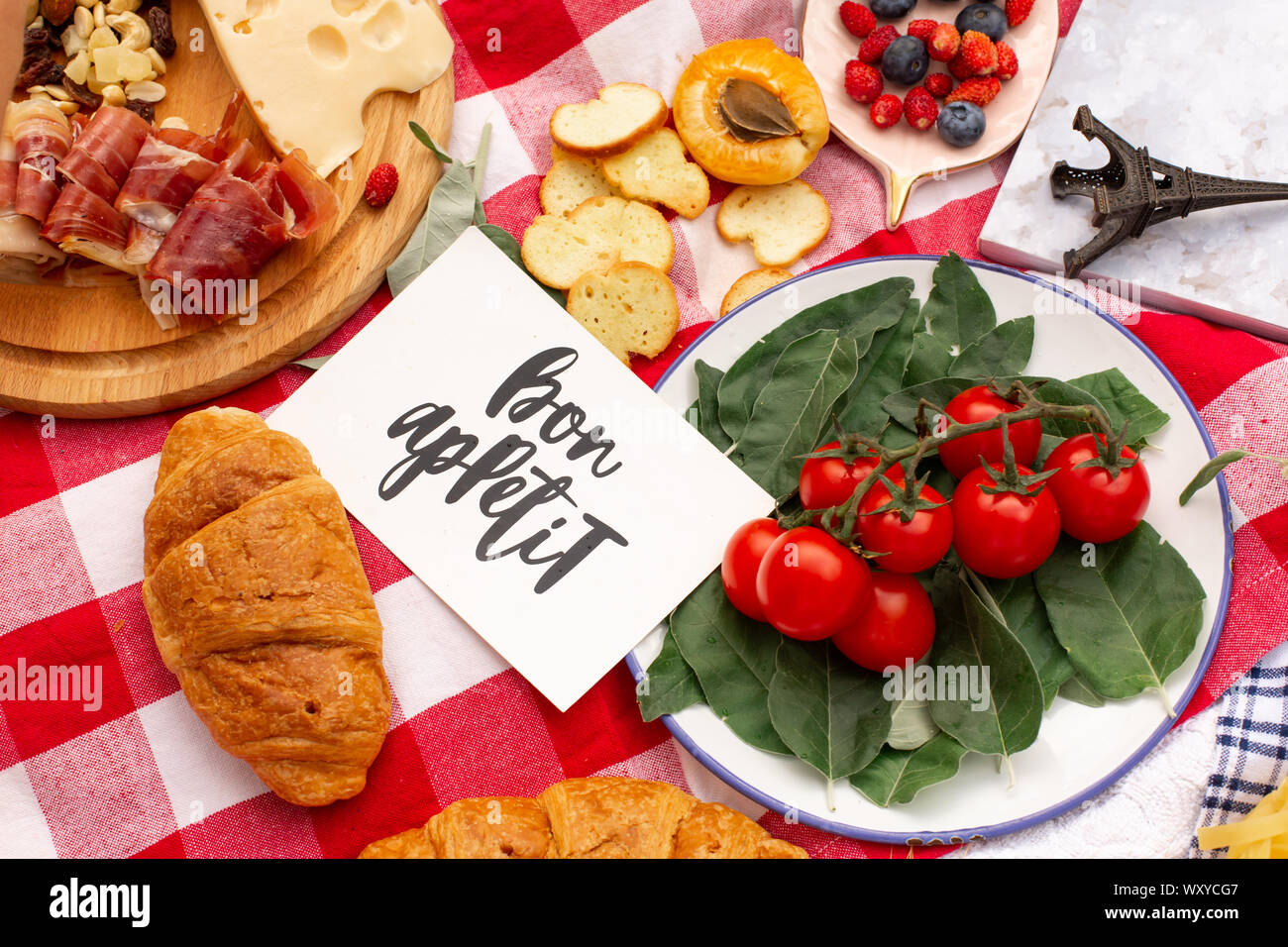 Elegante pic nic sul prato verde. Cornetti freschi e una teiera con il tè su un copriletto vicino a una femmina di vimini hat. Instagram contenuto. Foto Stock