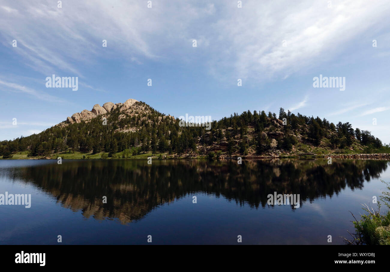 Le montagne circostanti il lago del Giglio nel Parco Nazionale delle Montagne Rocciose si riflettono nelle calme acque di estate del lago. Foto Stock