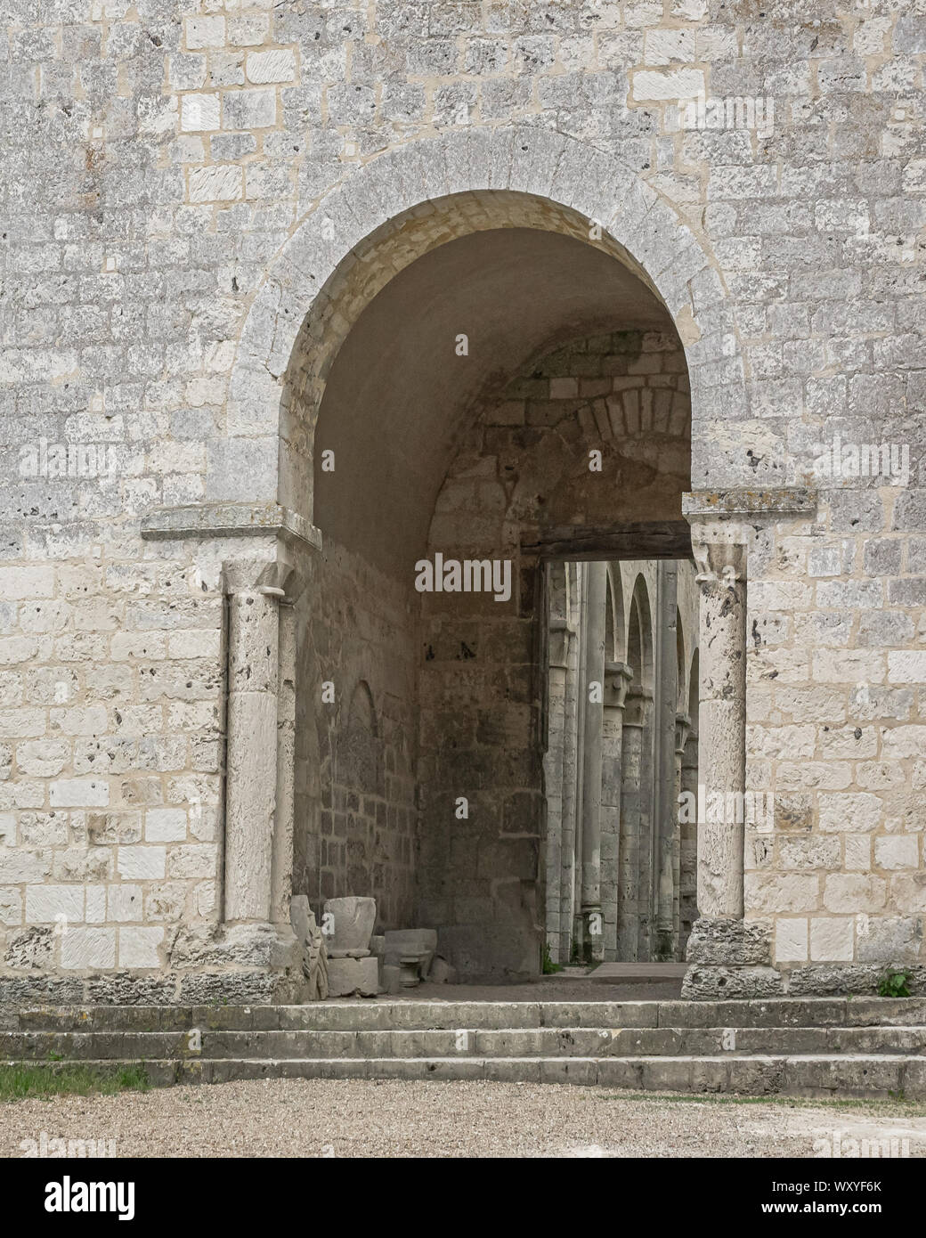 Bianco parete in pietra con ingresso ad arco, con rotture di scultura, e colonne visibile oltre alla rovina xi secolo Jumieges Abbazia in Normandia Francia. Foto Stock