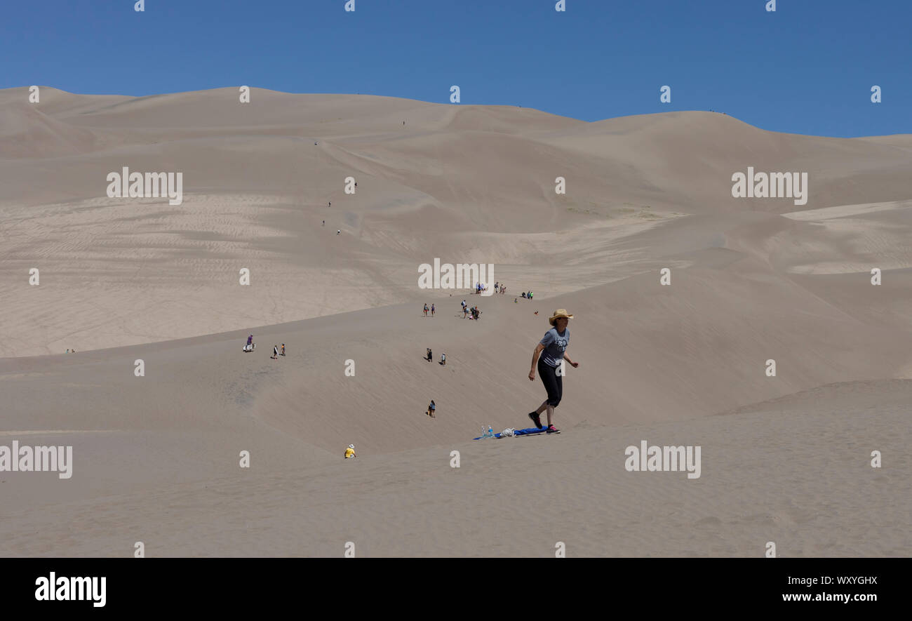 Gli escursionisti e sabbia sledders salire le dune a grandi dune di sabbia del Parco Nazionale durante il periodo estivo in Colorado. Foto Stock