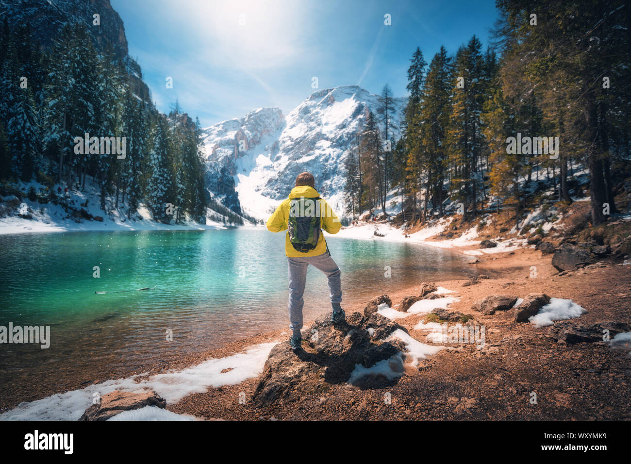 Uomo con zaino sulla pietra vicino al lago con acque azzurre Foto Stock