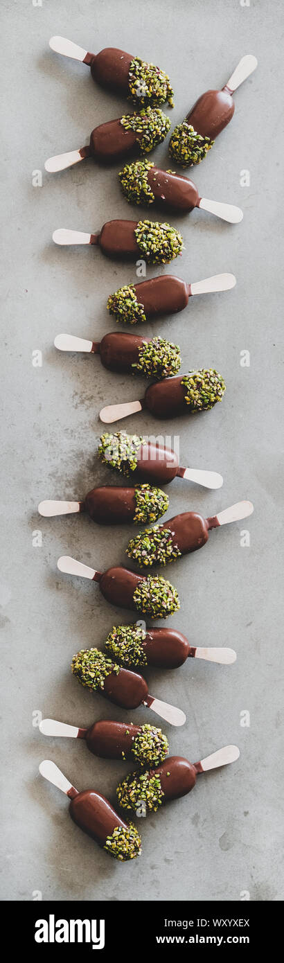 Flat-lay di vetri di cioccolato gelato pop su sfondo grigio Foto Stock