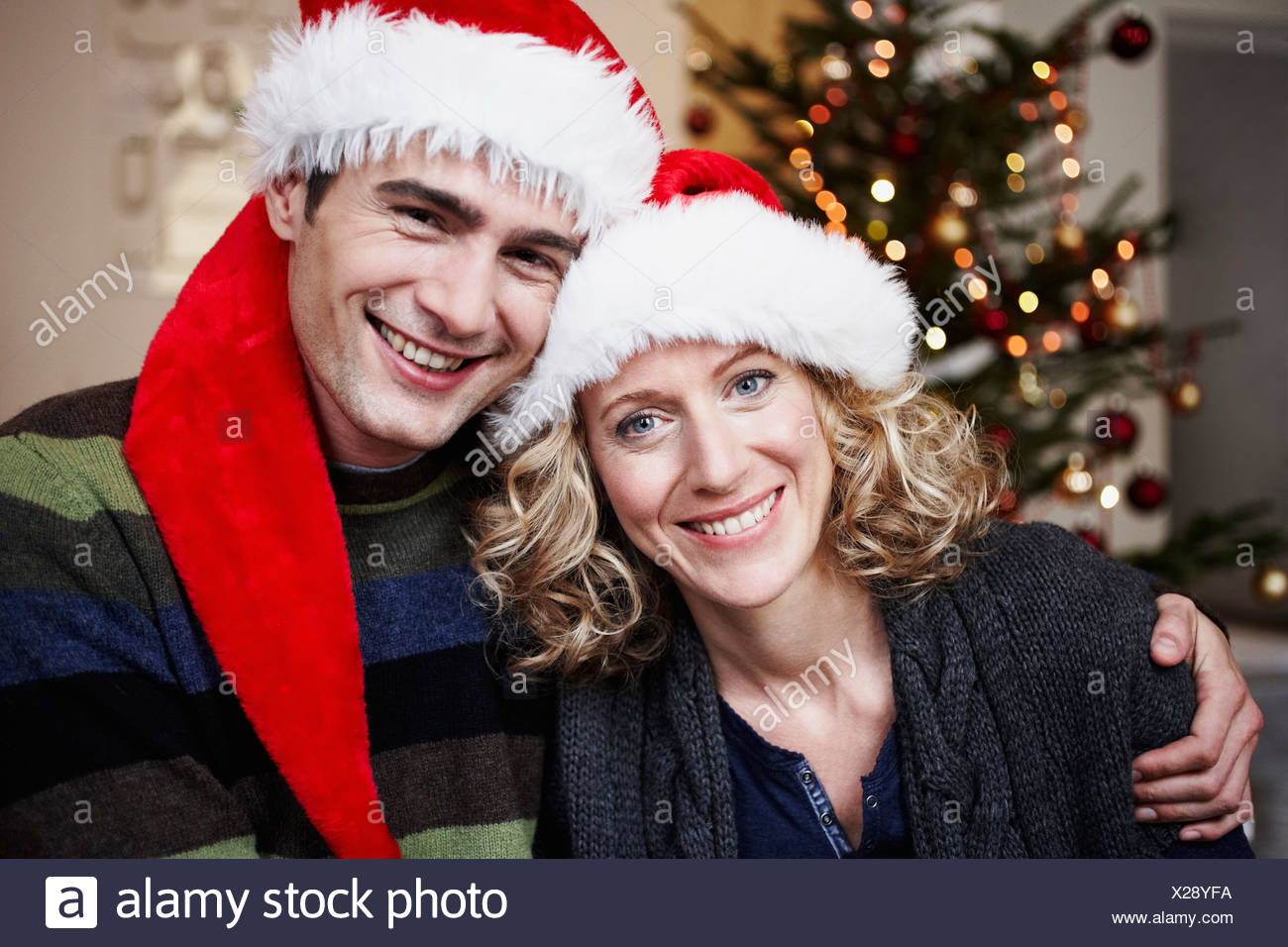 Immagini Del Cappello Di Babbo Natale.Coppia Con Cappelli Di Babbo Natale Nella Parte Anteriore Della Struttura Ad Albero Foto Stock Alamy