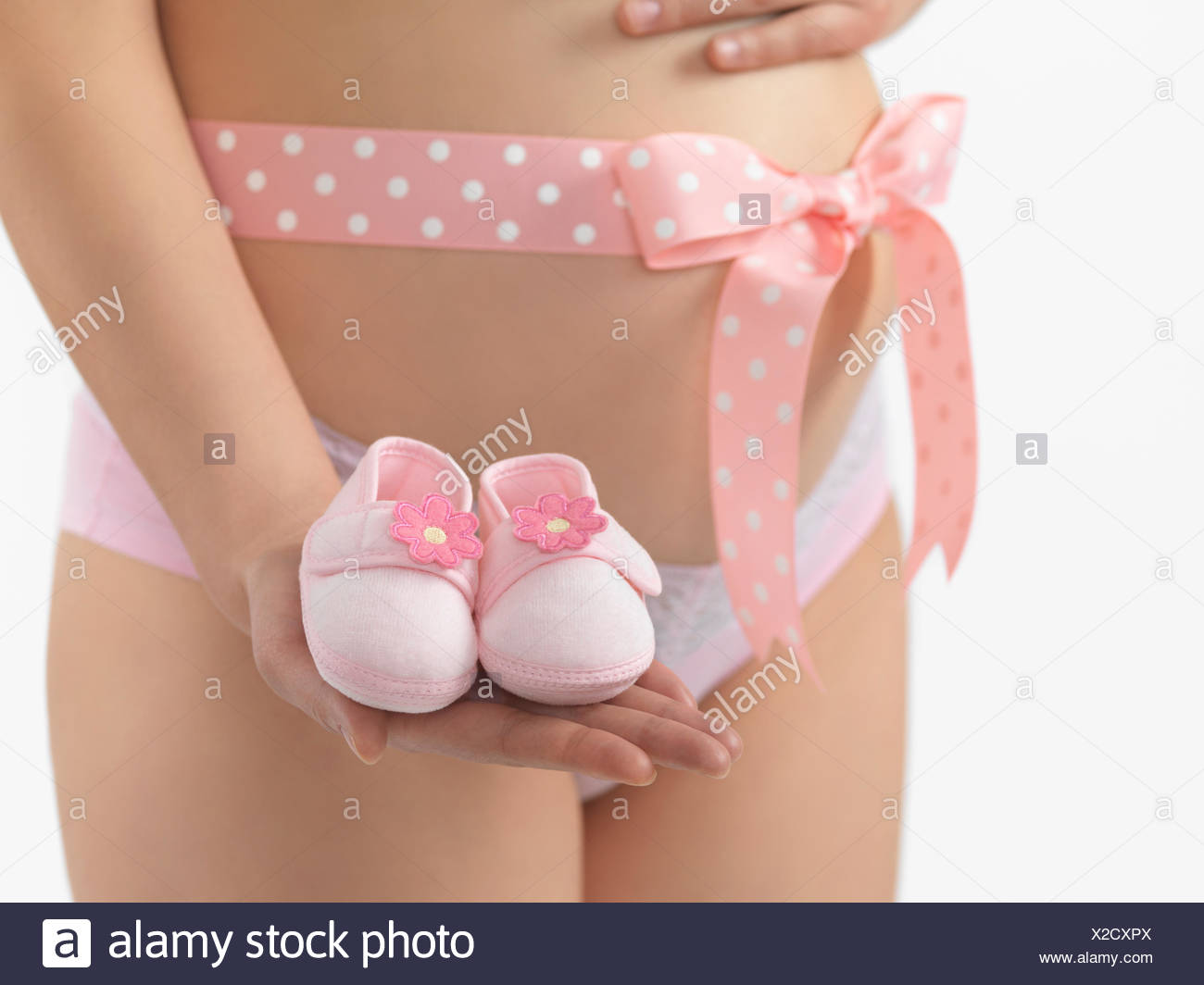 Donna Incinta Con Un Fiocco Rosa Intorno Al Suo Ventre Holding Baby Scarpine In Mano Foto Stock Alamy