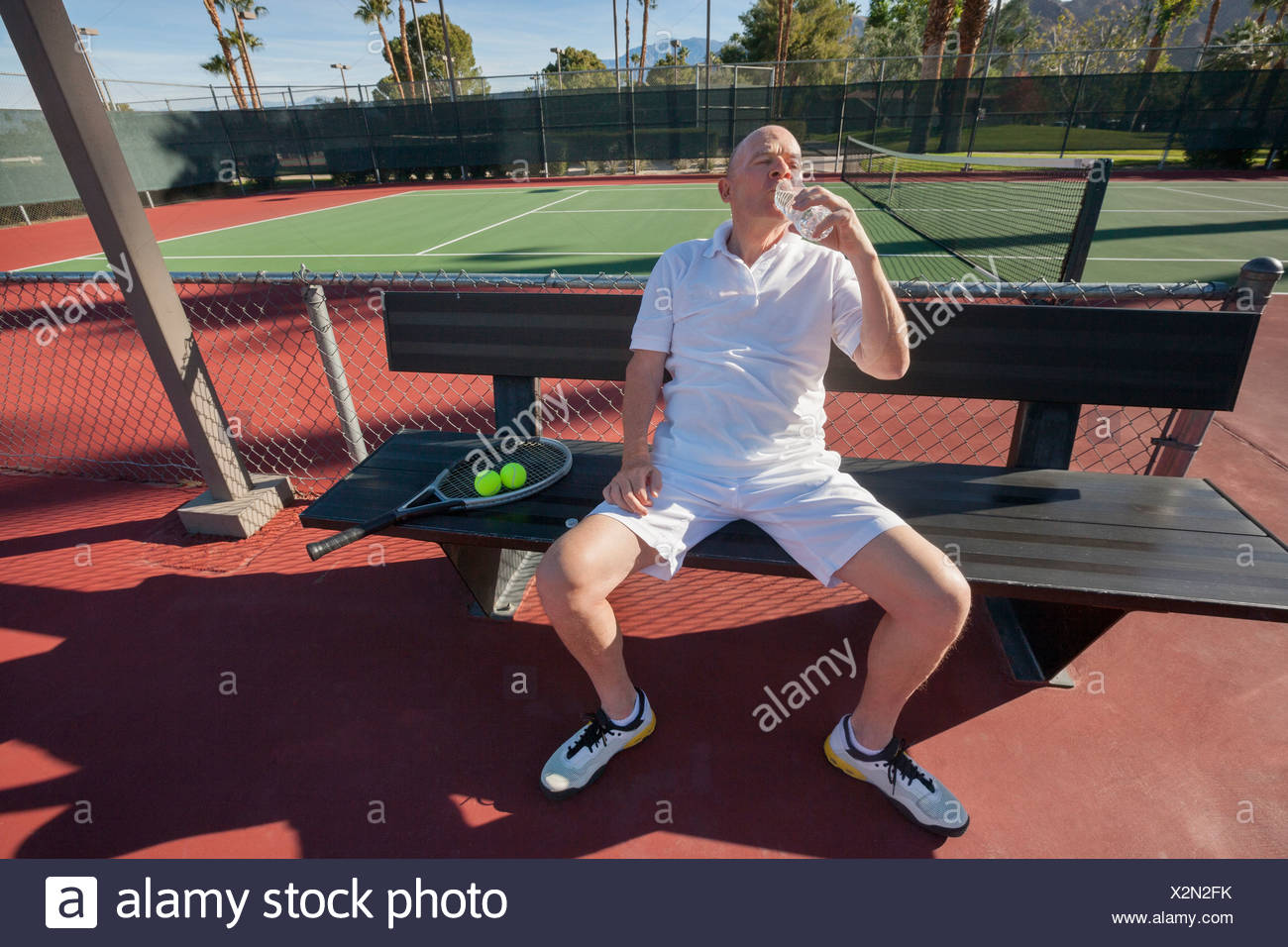 Senior tennista acqua potabile mentre vi rilassate sulla corte Foto Stock