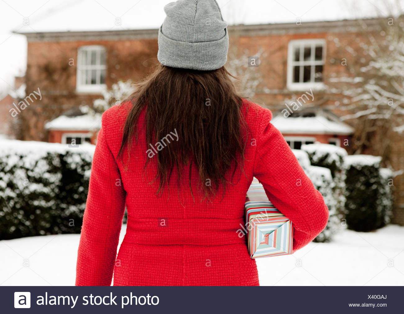 Donna che trasportano dono avvolto nella neve Foto Stock