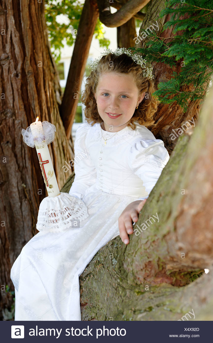 Prima Comunione Bambina Con Un Abito Bianco Seduto Su Una Struttura Ad Albero Foto Stock Alamy