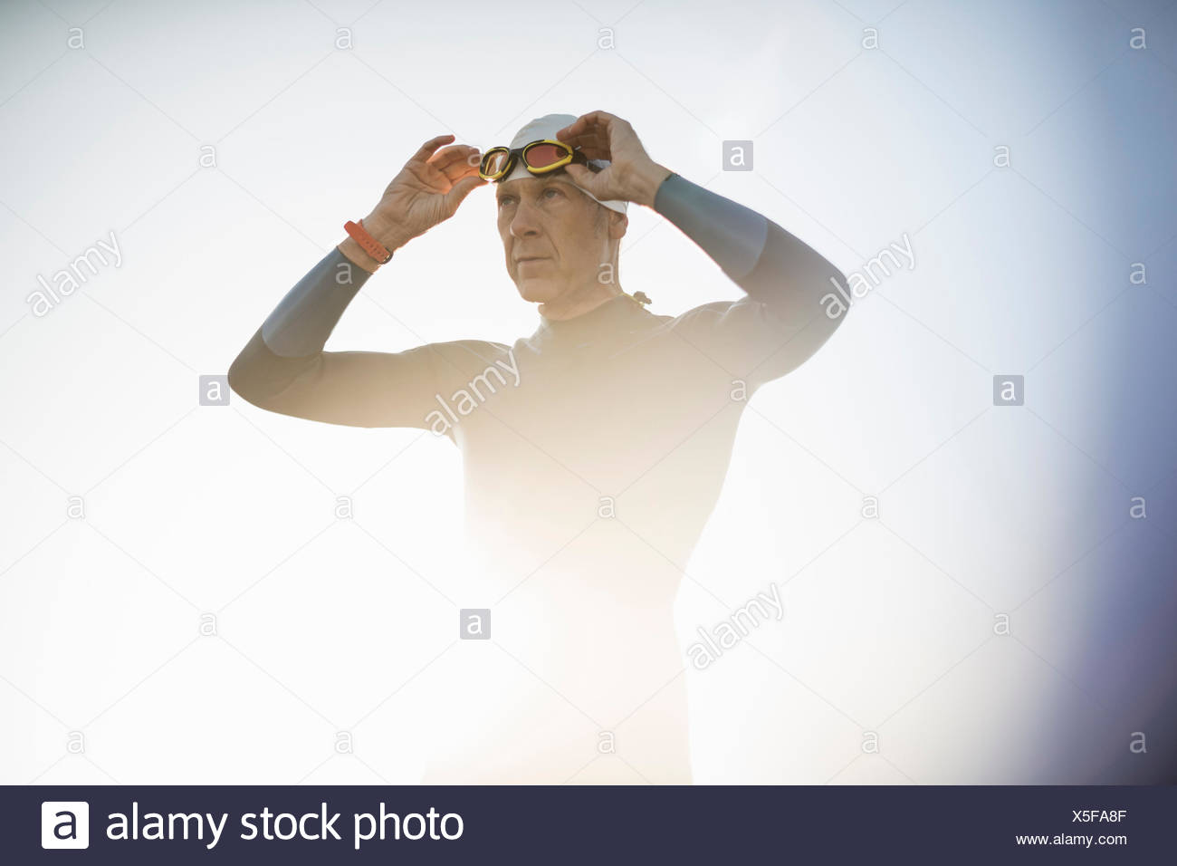 Un nuotatore in una muta e nuoto hat, regolando i suoi occhiali da nuoto. Foto Stock