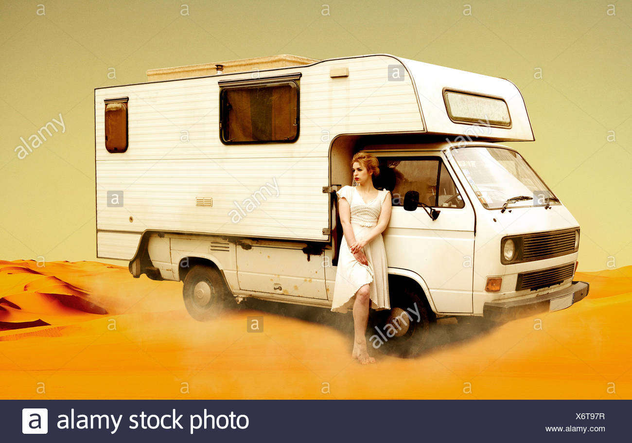 Germania, Berlino, giovane donna in piedi accanto al bus di campeggio nel deserto Foto Stock